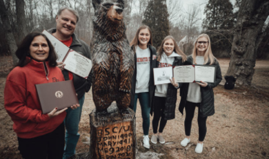 The McDonough family poses by their carved bear statue