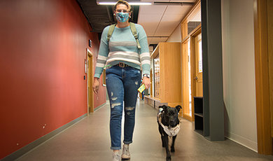 Bethany Roderick and her service dog walk down a hallway.