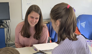  Adlai Greene works with a female student at a table.