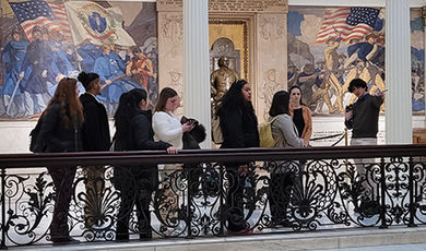 Students on the alternative spring break program walk by a mural inside the Statehouse