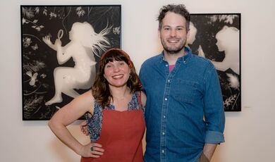 A man and woman stand next to each other smiling 