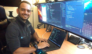 Brenner Campos works at a desk with multiple computer monitors.