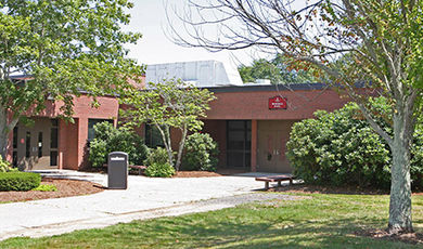 Burnell Hall as seen in summer with several trees in front of the building.
