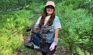 While walking in the woods, Sarah Calis holds a crate used for her research.