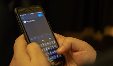 A person writes a social media post on a cell phone.