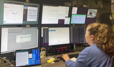 Shannon McLaughlin types while sitting in front of a large display of monitors.