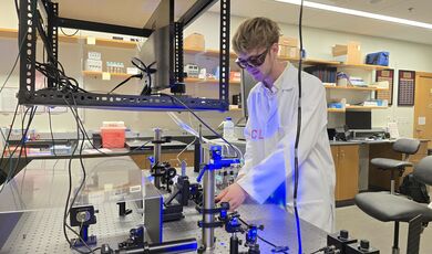 Christopher Leary works with optical equipment in a lab.