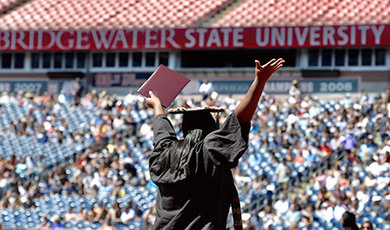A graduate raises their hands in front of a crowd.