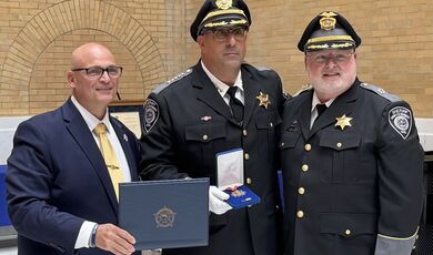 Three men stand together holding an award