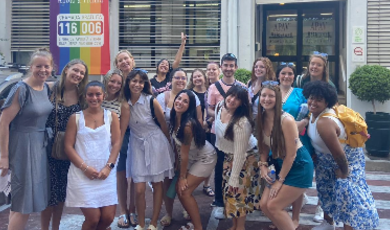 A group of people stand together to pose for photo with smiles on their faces 