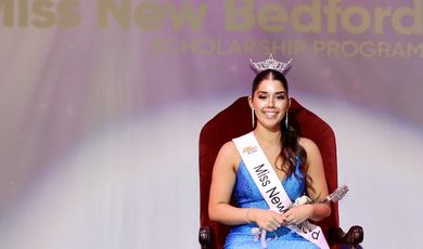 Emma Gendreau wears a crown sitting in a chair with a Miss New Bedford sash on