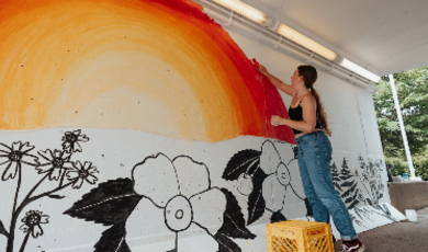 Samantha Cushing is standing and painting on the tunnel wall 