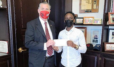 Dabana Intenque receives a scholarship check from President Clark