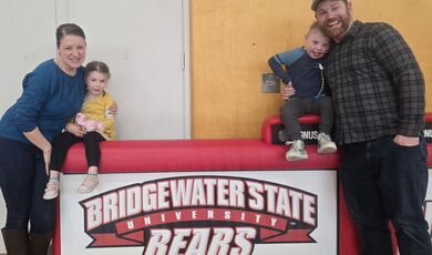 A woman, man and two small children stand in front of a sign that reads Bridgewater State University
