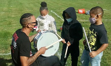 Greg Fernandes gives a drum lesson to three kids.