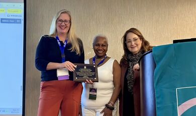 M. Nikki Freeburg receives an award from two presenters.