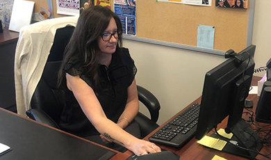 Diane Heath sits at a desk and moves a computer mouse.