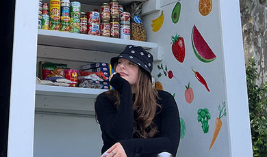 Kellie sits in front of shelves filled with food.