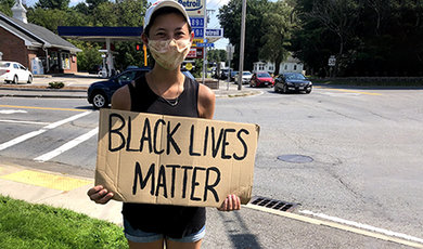 Jasmine Won holds a Black Lives Matter sign beside a road.