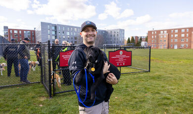 A man smiles holding a dog