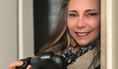 A woman smiling holding a camera 