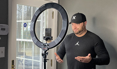 Keith Gilchrist records a TikTok video using a ring light.