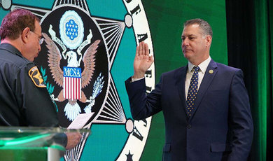 Peter Koutoujian, '83, right, is sworn in by outgoing Major County Sheriffs of America President Grady Judd. 