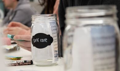 A jar sits on a table with the label self care written on it
