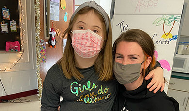 Nikki Maloney poses for a photo in a classroom with a student.
