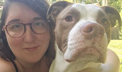 A woman wearing glasses poses with her dog 