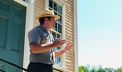 Mark Mello speaks while standing in front of a historic building.