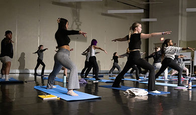 Students twist their bodies and extend their arms during a yoga exercise.
