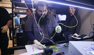 Samuel Bechtold works with wires in a photonics lab.