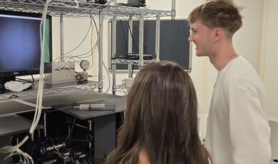 Two students work with optical equipment in a lab.