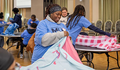 Students fold blankets as part of a service project.