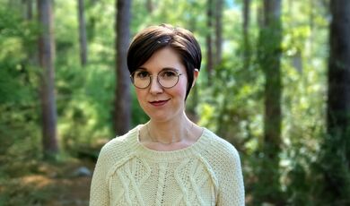 Sarah Fawn Montgomery stands in front of trees.