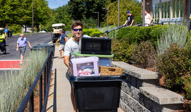 A man wearing sunglasses pushes a cart with many items in it