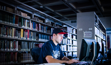 Student sits in library and works on computer