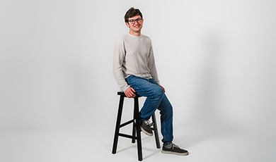 Paul Ridikas poses for a photo while sitting on a stool.