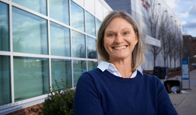 Woman stands smiling with arms crossed in front of her