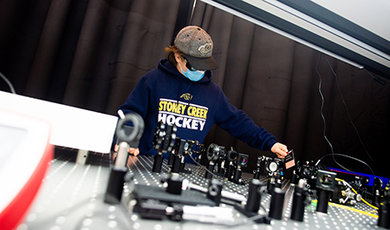 Peyton Brown adjusts photonics instruments mounted to a lab table