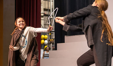 Two students rehearse a scene using a broken hanger as a prop.
