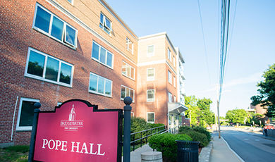 The exterior of Pope Hall, with a red sign for the building in the foreground