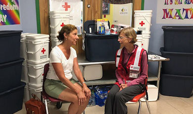 Maggie Lowe, wearing a Red Cross vest, talks with a flood victim.