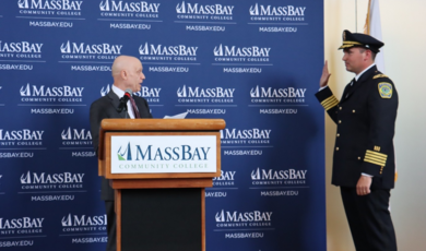 A man wearing a police uniform has his hand up and is sworn in