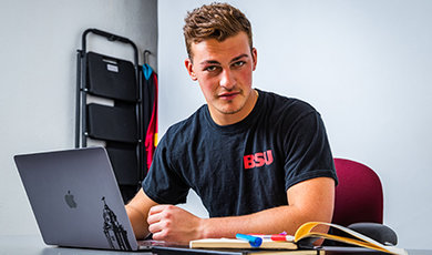 Ryan Kuczer sits at a desk working on a laptop