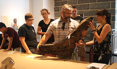 Calvin Mires lifts a timber from the Sparrow-Hawk onto a table.