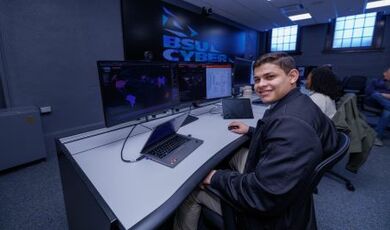 An intern works at computers in the Security Operations Center