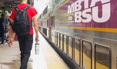 A man wearing a backpack walks towards a train