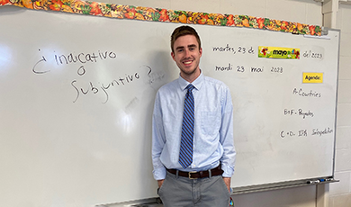 Jake Murray stands in front of a white board in a classroom.